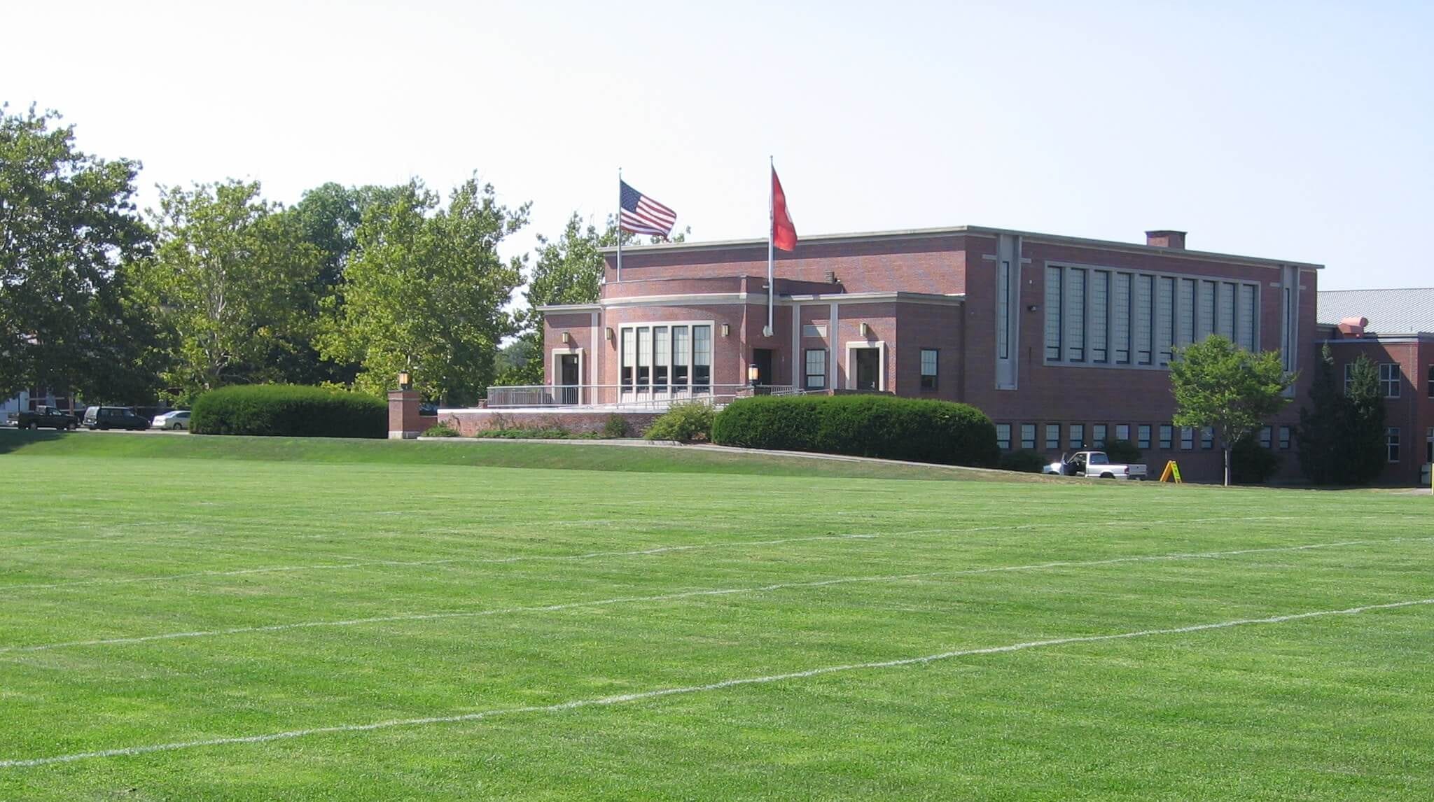 School with large field in front that's used organic fertilizer