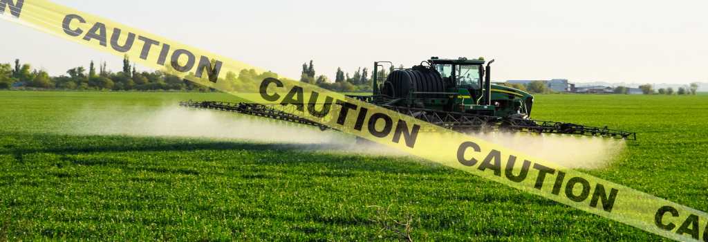 tractor spreading toxic chemicals on fields with caution tape on the foreground of the photo